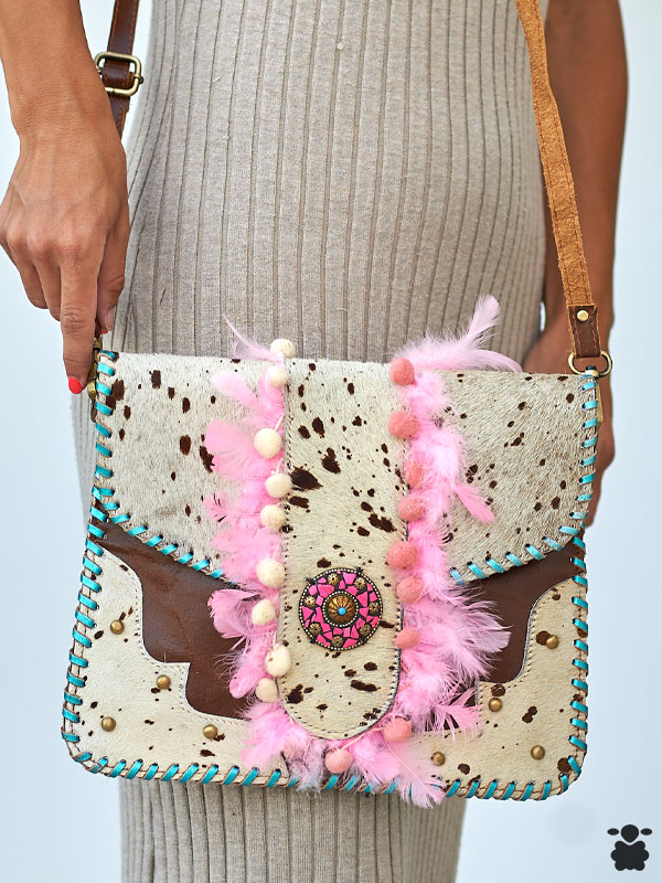 Bolso boho chic de piel con plumas rosas y pompones decorativos.