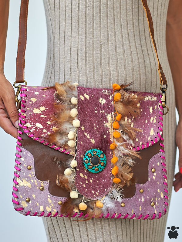 Bolso boho chic de piel con plumas granate y pompones decorativos.